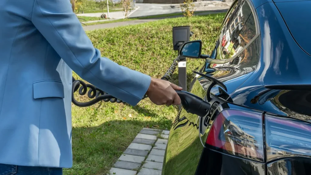 A woman plugging in an EV charger in public