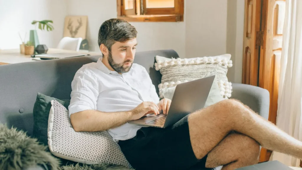 a person sitting on the couch researching about EVs on a laptop